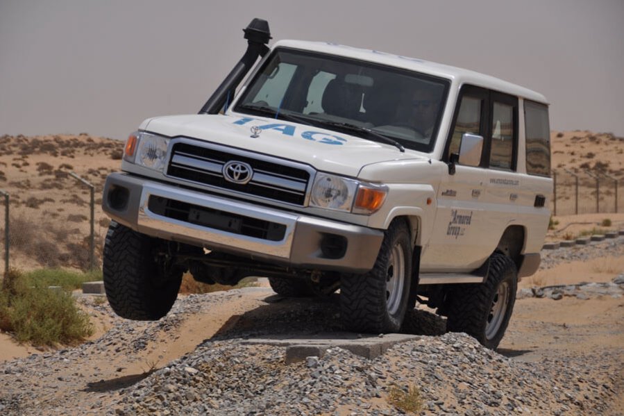 TAG White armored Toyota Land Cruiser (TLC) 76 Series cash-in-transit SUV with upgraded suspension in the desert